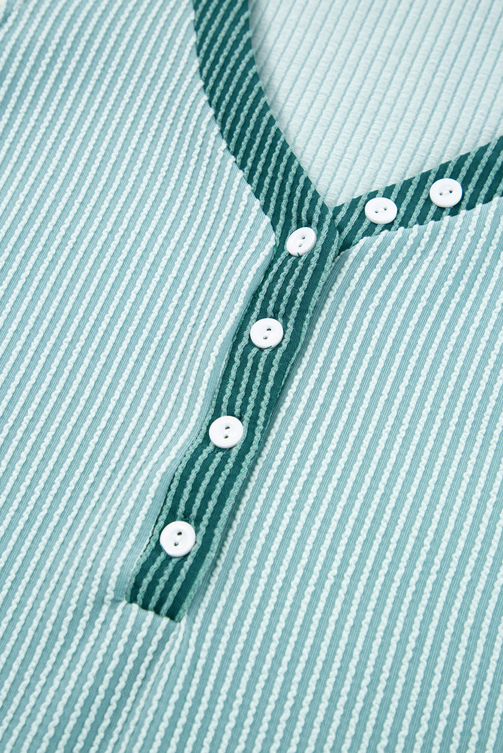 Mint zelena majica s kontrastnim gumbima i teksturiranim V izrezom
