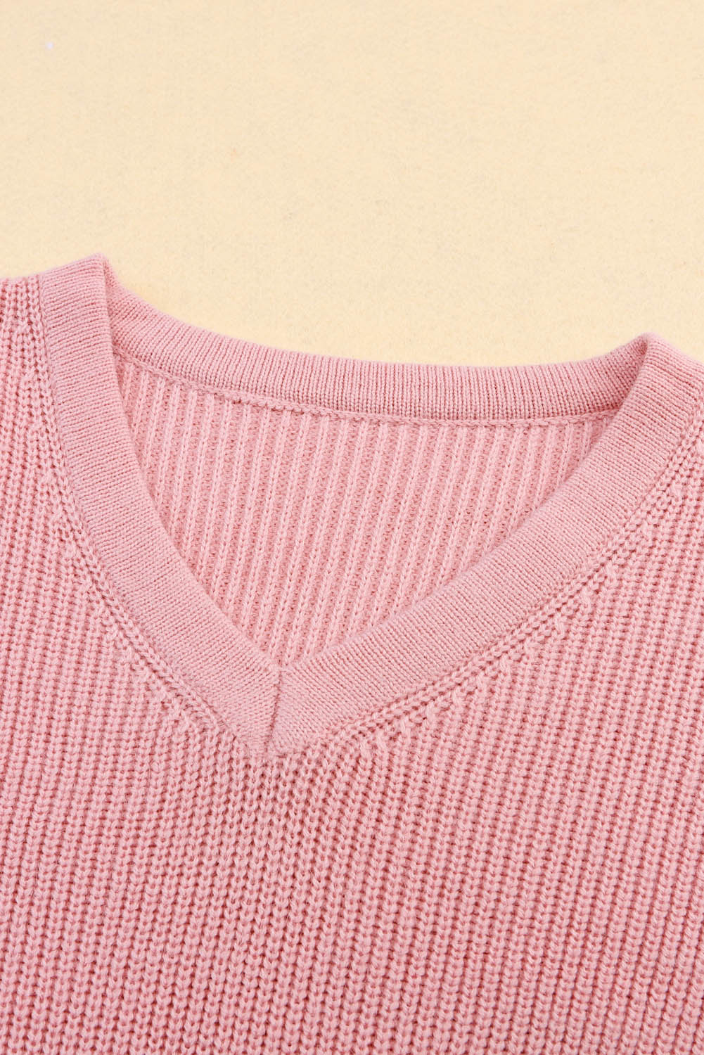 Ružičasti pleteni pulover s V izrezom i spuštenim ramenima