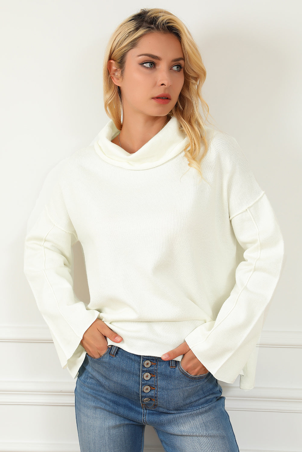 Preveliki pulover s bijelim otvorenim šavovima s kornjačinim izrezom i bočnim prorezom