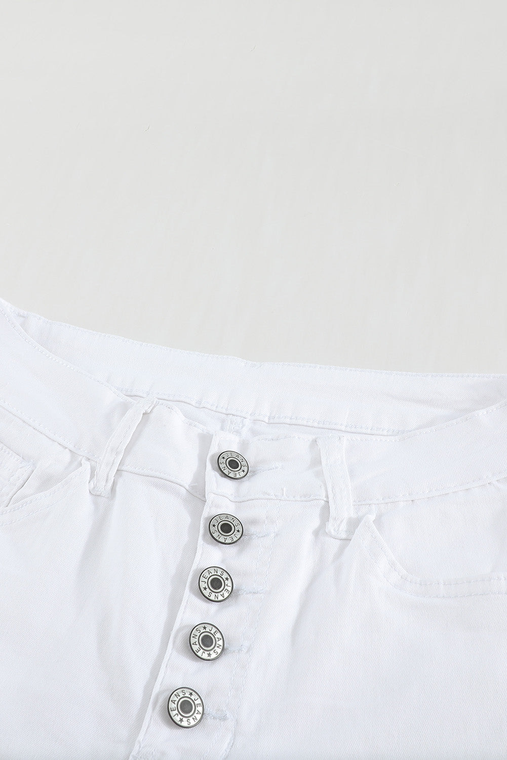 Jednobojne bijele traperice s dugmadima visokog struka