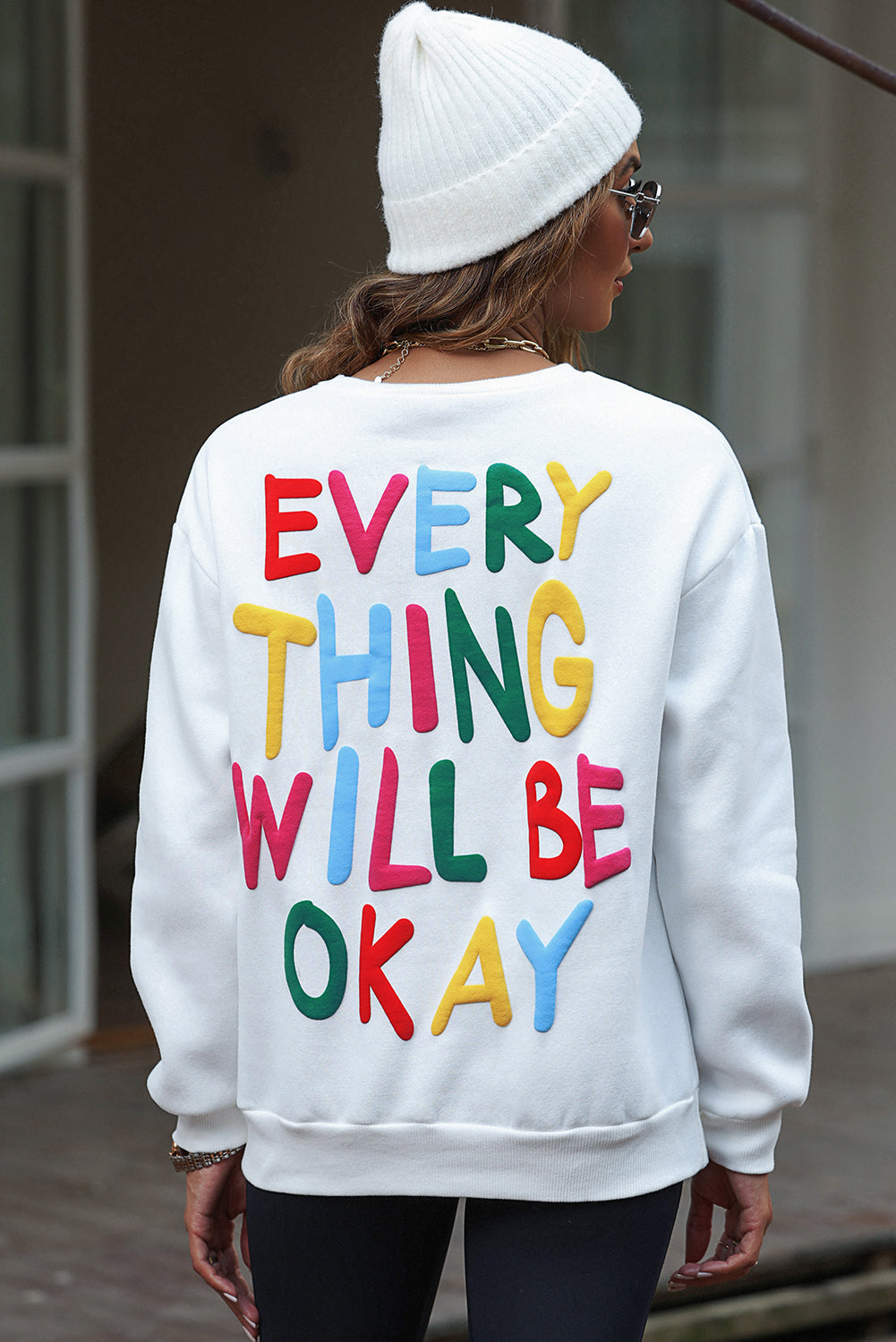 Weißes Sweatshirt mit bunten Buchstaben „EVERY THING WILL BE OKAY“.