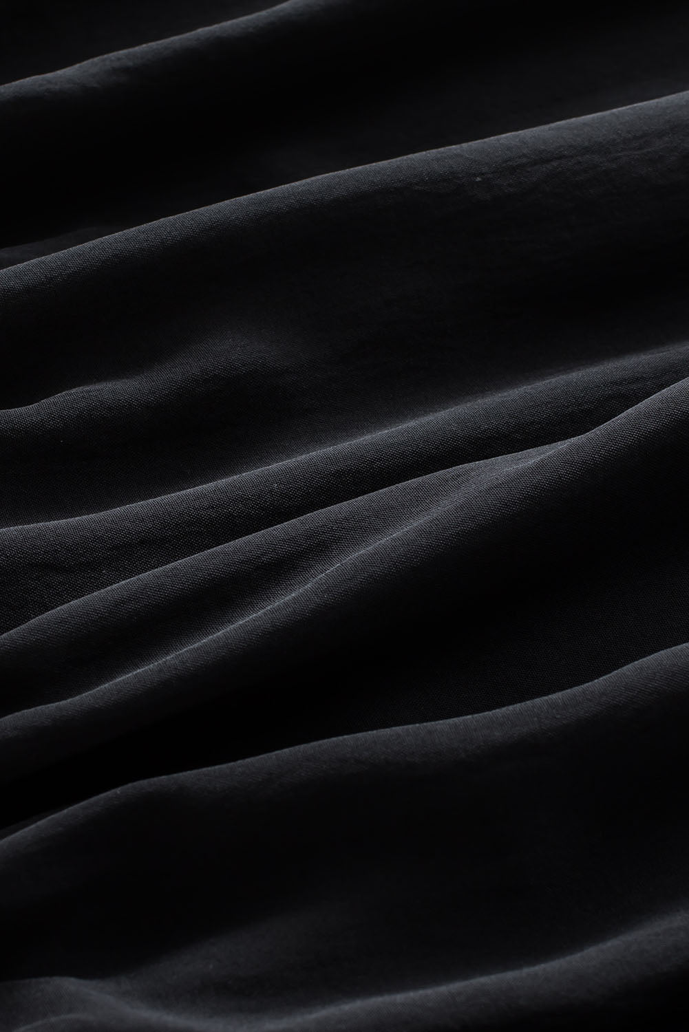 Schwarze, plissierte, lockere Bluse mit gepolsterten Schultern und geknöpften Manschetten