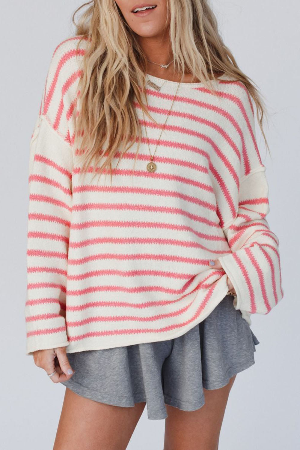 Prevelik pulover z rožnatimi črtami na spuščena ramena
