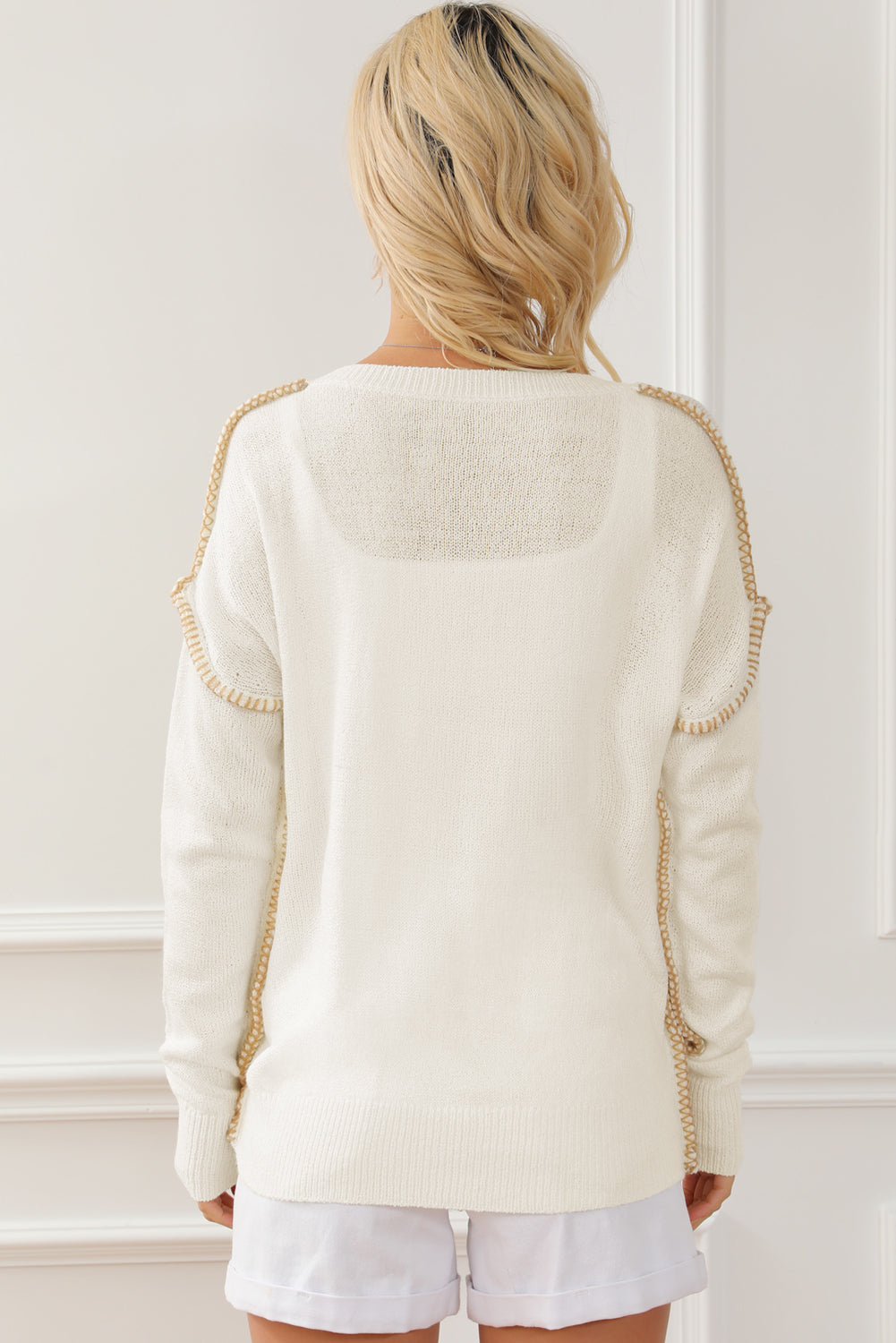 Beigefarbener Pullover mit freiliegenden Nähten auf der Brusttasche und überschnittener Schulter