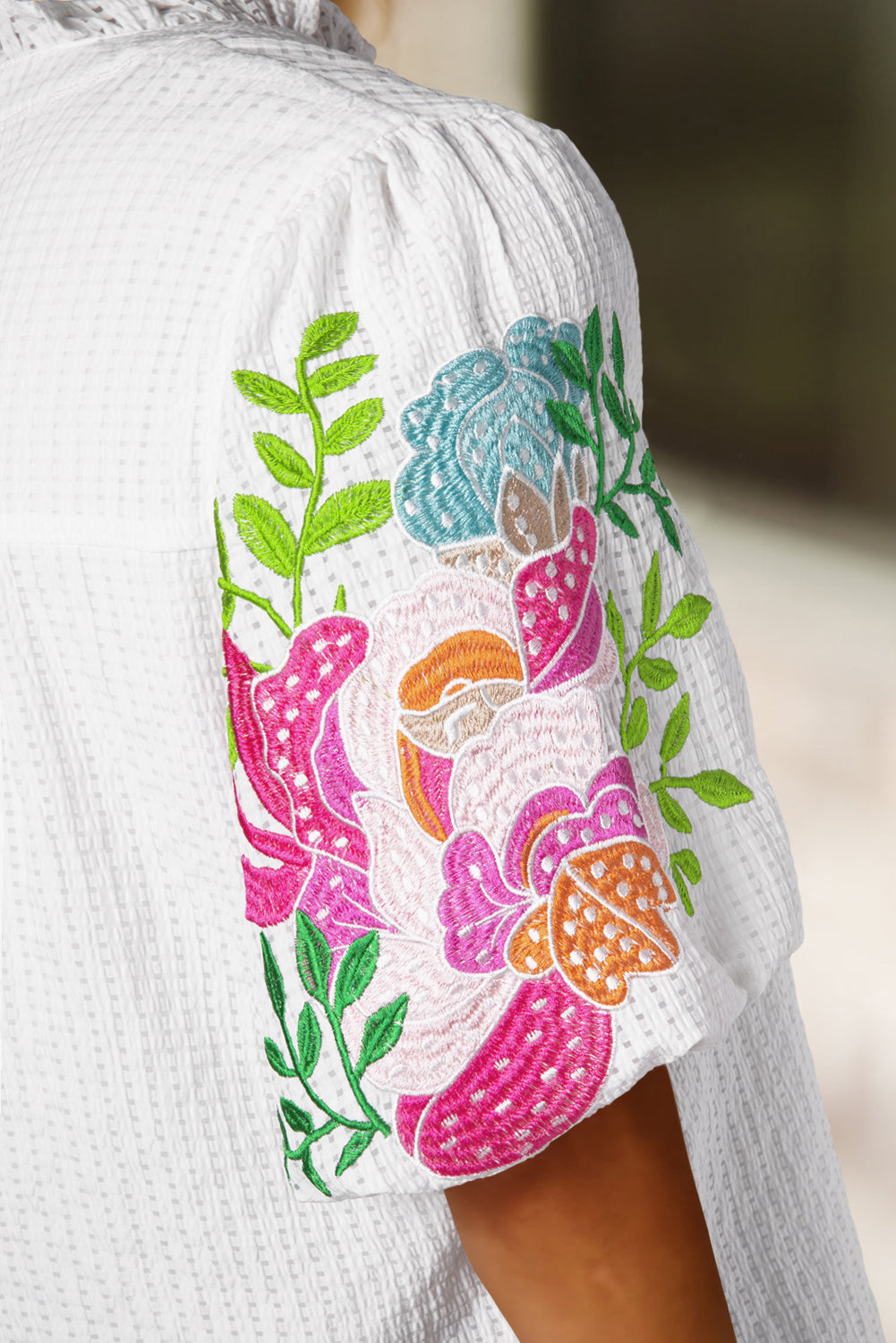 Bela bluza z izvezenimi cvetličnimi rokavi in ​​zarezanim ovratnikom