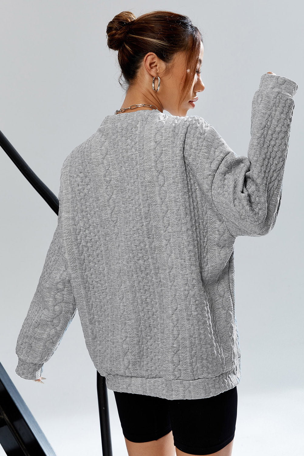 Sivi pulover s kabelskom teksturom na spuštena ramena