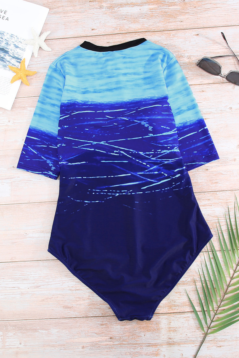 Jednodijelni kupaći kostim s plavim printom i patentnim zatvaračem sprijeda do pola rukava
