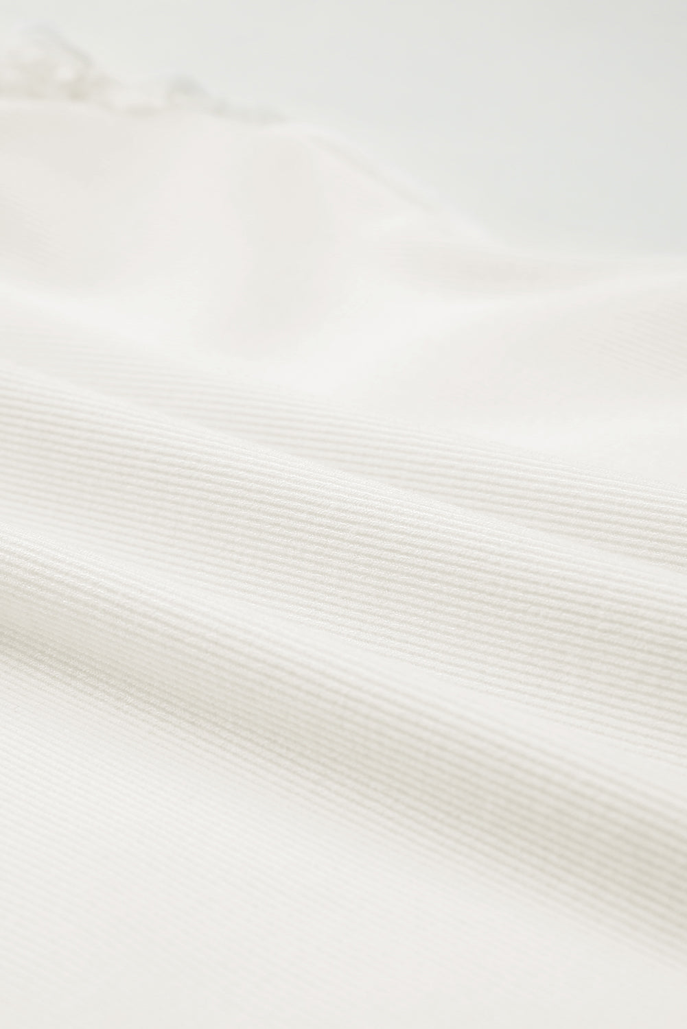 Bela rebrasta pletena majica z v-izrezom in plapolami na ramenih