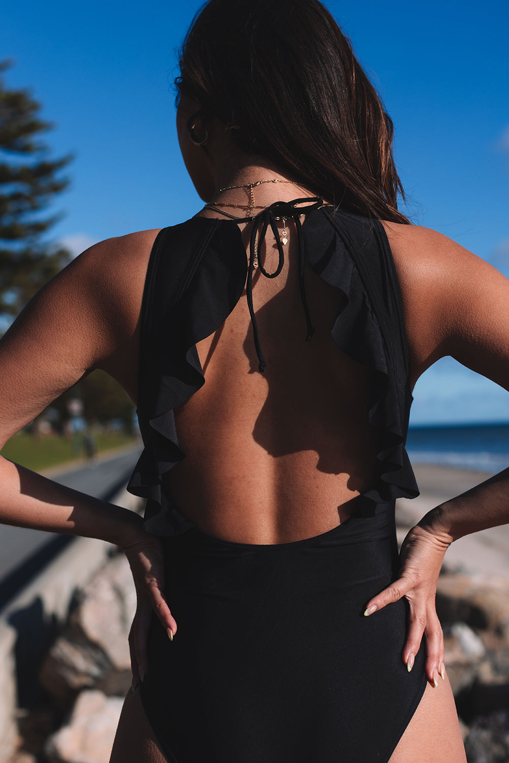Crni jednodijelni kupaći kostim otvorenih leđa s naborima na vezivanje