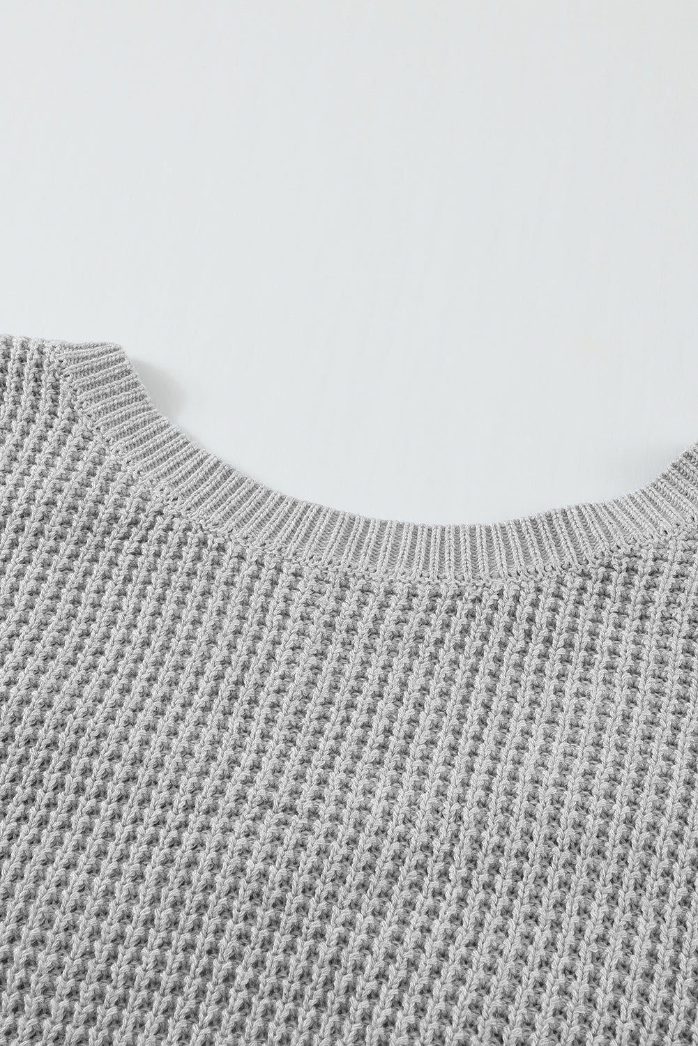 Sivi pulover s izdubljenom pozadinom