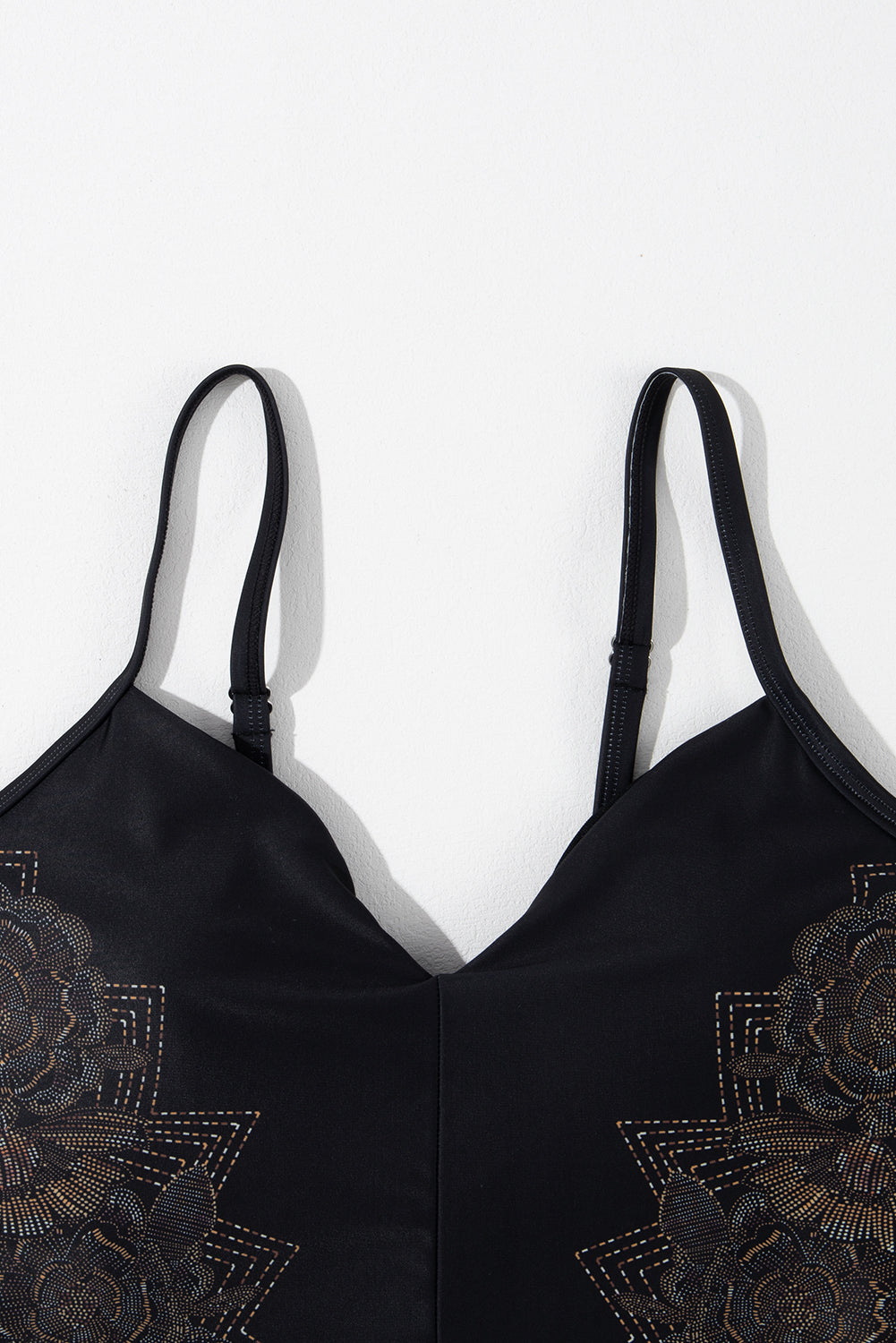 Schwarzer Badeanzug mit überkreuzten Spaghettiträgern und Blütenblattmuster am Rücken