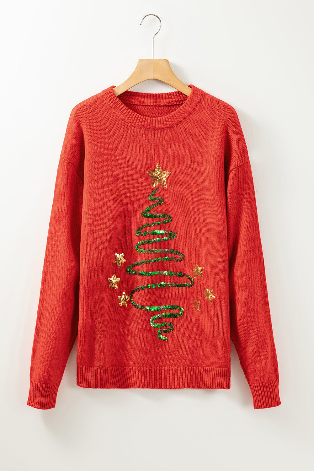 Vatrenocrveni pulover s skicom božićnog drvca sa šljokicama na spuštena ramena