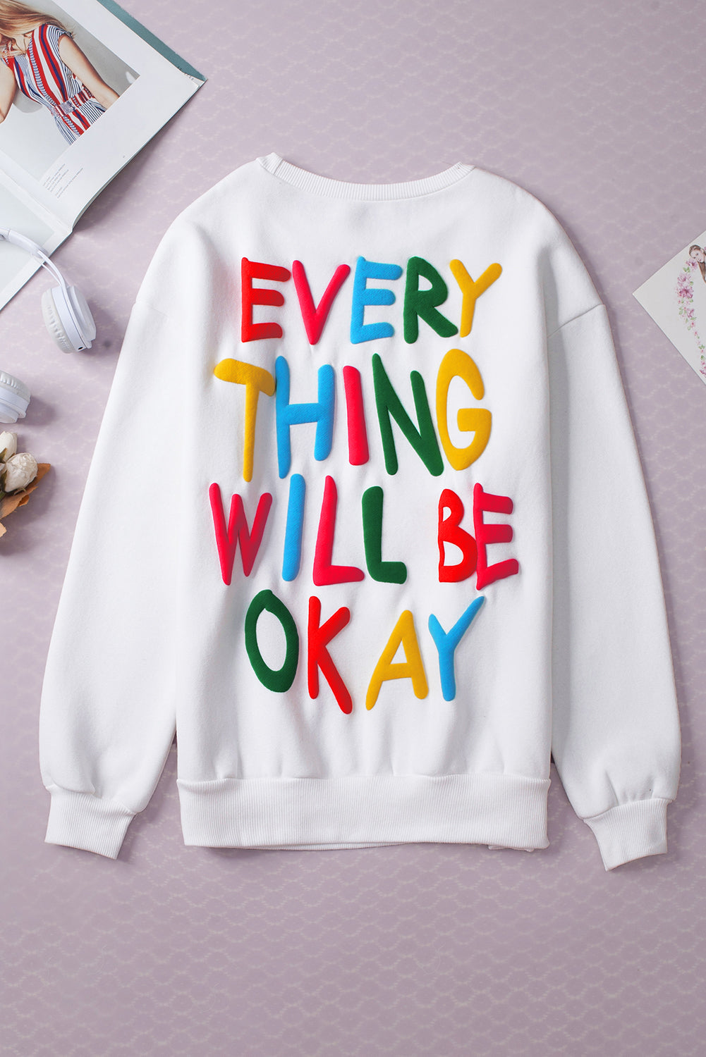 Weißes Sweatshirt mit bunten Buchstaben „EVERY THING WILL BE OKAY“.