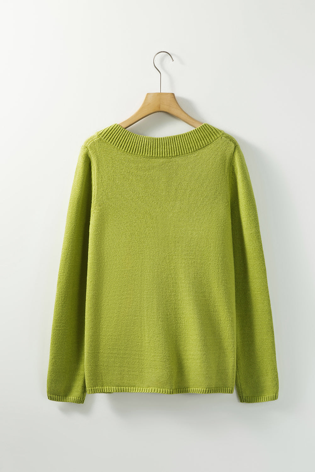 Enobarvni pulover z zelenim gumbom in v-izrezom