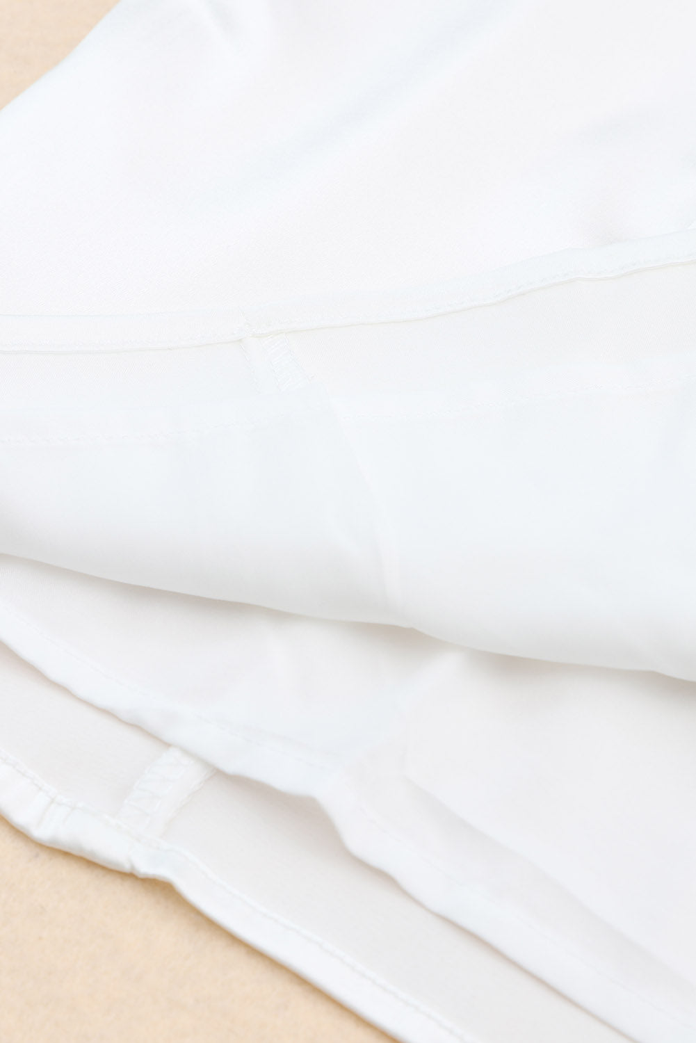 Bela puhasta mini obleka brez naramnic, obrobljena s perjem
