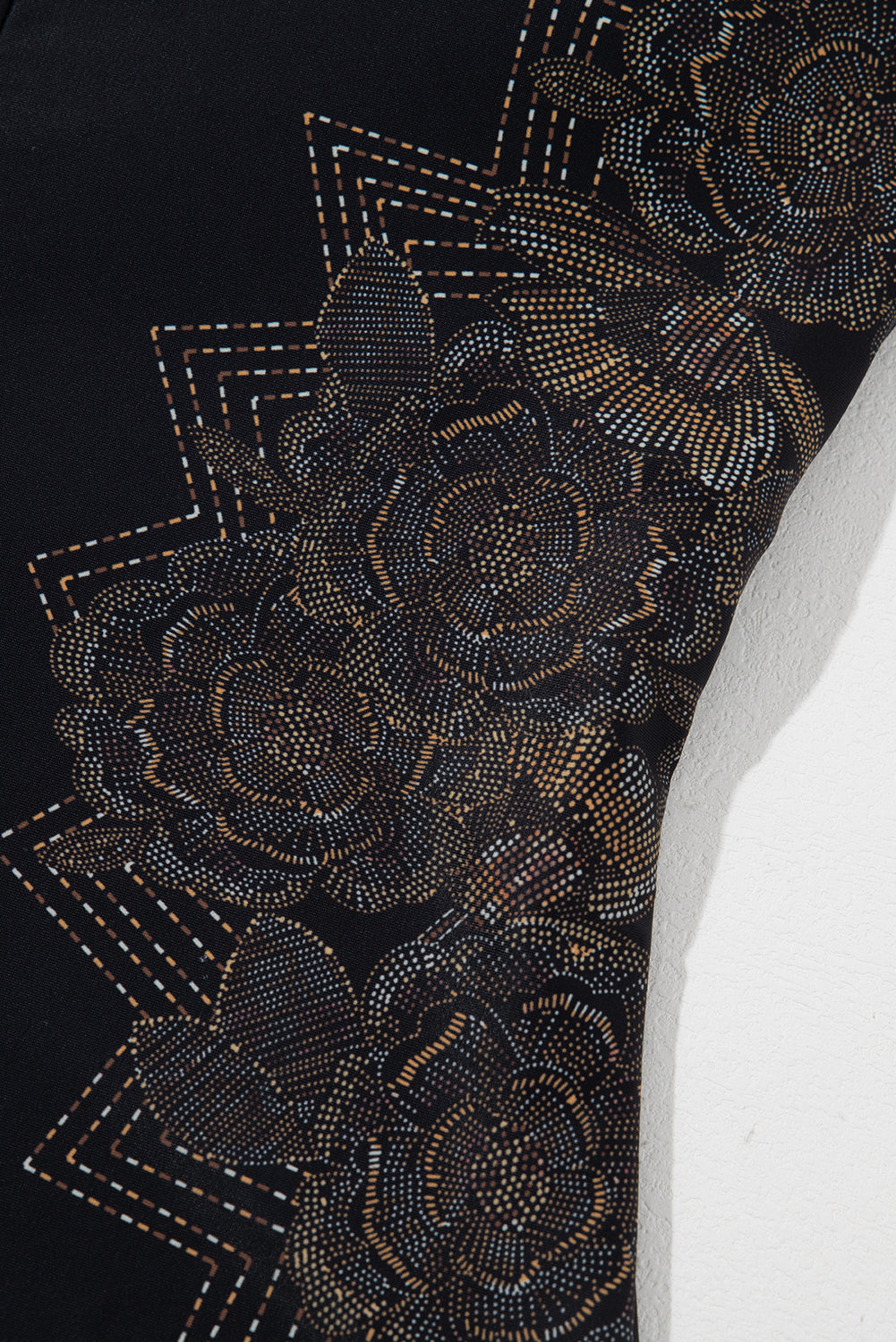 Schwarzer Badeanzug mit überkreuzten Spaghettiträgern und Blütenblattmuster am Rücken